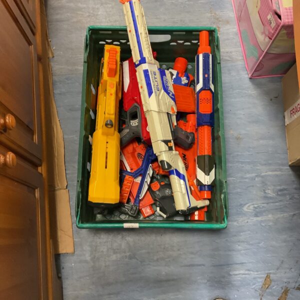 Crate filled with a variety of Nerf guns and foam dart blasters.