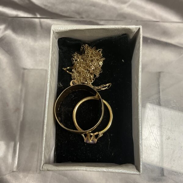 Close-up of 9ct gold scrap jewellery lot including rings and necklaces.