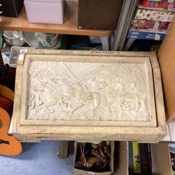 Carved sandstone wall plaque featuring horses, rustic garden art.
