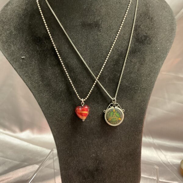 Silver pendant necklaces with enamel coin and stone heart designs.