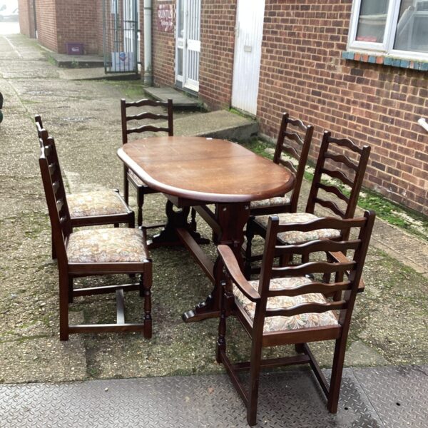Vintage oak extending dining table and six chairs in a garden setting.