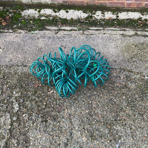 Brightly coloured coiled rubber garden hose for outdoor watering.