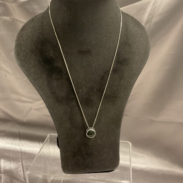 Silver pendant necklace with Korite stone on black display.