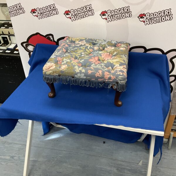 Vintage floral footstool with wooden legs, a charming home decor piece.