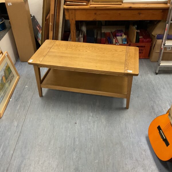 Rustic oak coffee table with lower shelf in a living room setting.