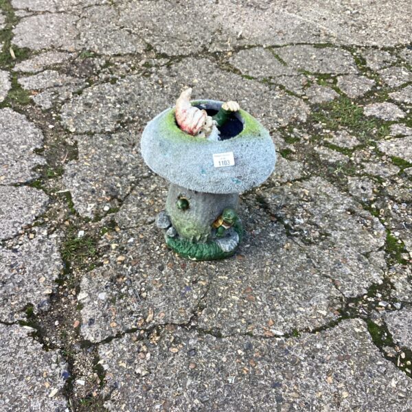 Whimsical garden gnome ornament nestled in a red toadstool.