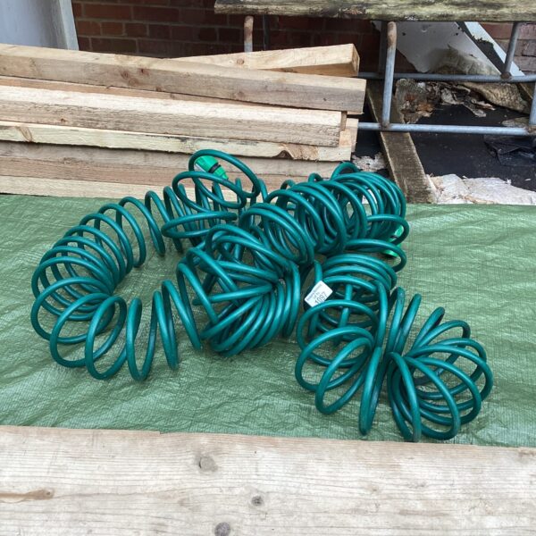 Bright green coiled rubber garden hose for watering lawns.