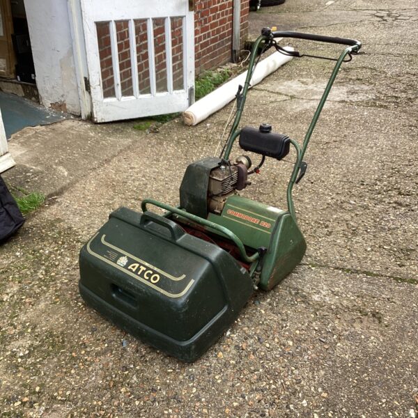 Vintage Atco Commodore B20 petrol lawn mower in garden setting.