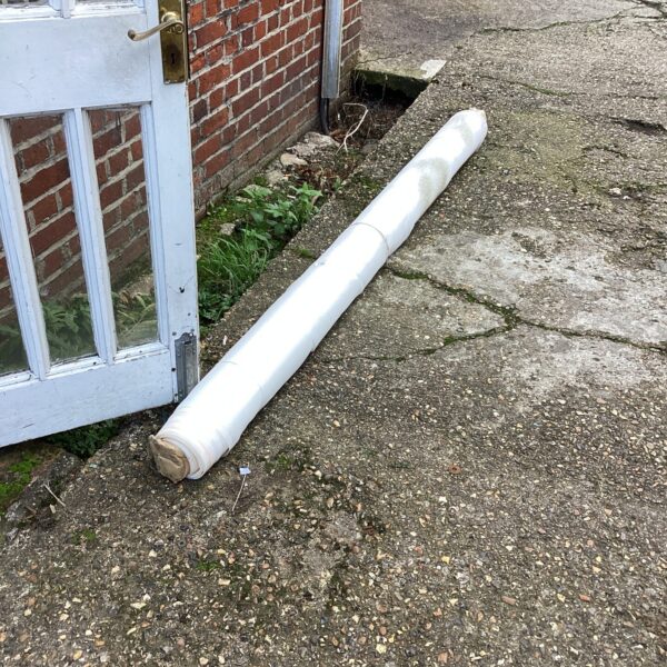 Roll of fine mesh material outdoors, suitable for screening.