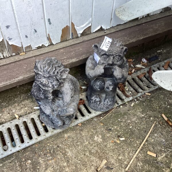 Pair of vintage imp garden ornaments in a garden setting.