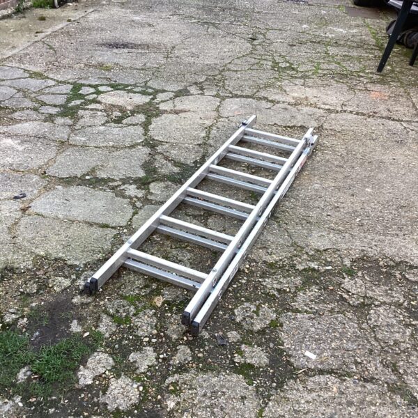 Silver aluminium extending ladder leaning against a wall.