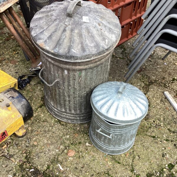 Two vintage galvanised garden bins in a garden setting.
