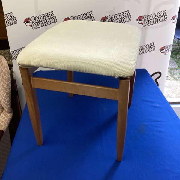 Vintage dressing table stool with patterned seat and wooden legs.