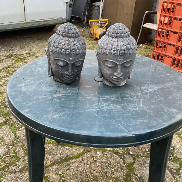 Weathered garden Buddha heads, stone effect outdoor decor.