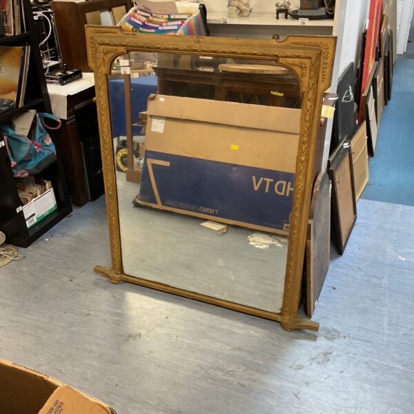 Large antique gilt framed overmantle mirror with ornate detailing.