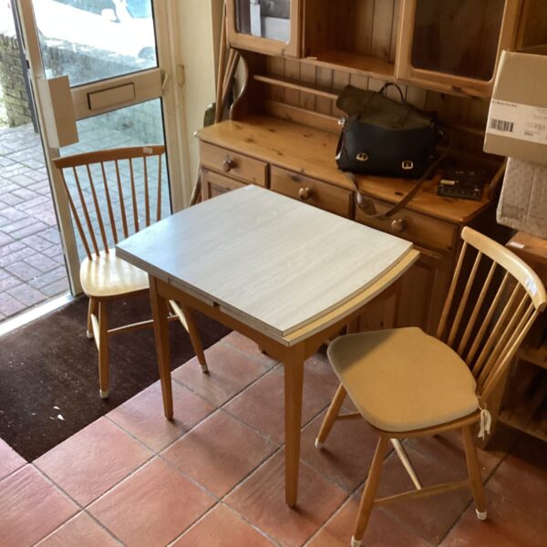 Vintage Formica extending table with two pine chairs in a retro kitchen setting.
