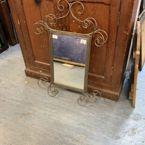 Antique wrought iron mirror with ornate botanical design.