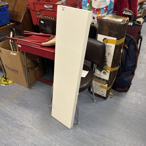 White floating shelf leaning against boxes and furniture.