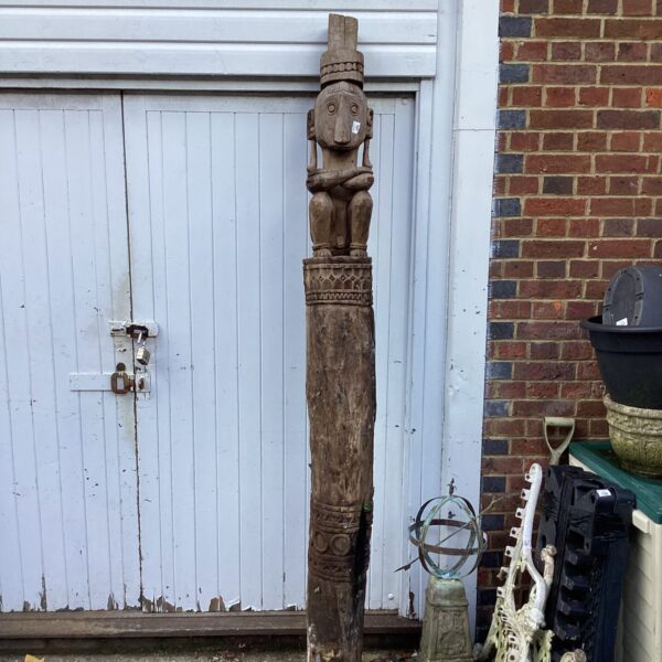 Large hand carved totem pole in a garden setting.