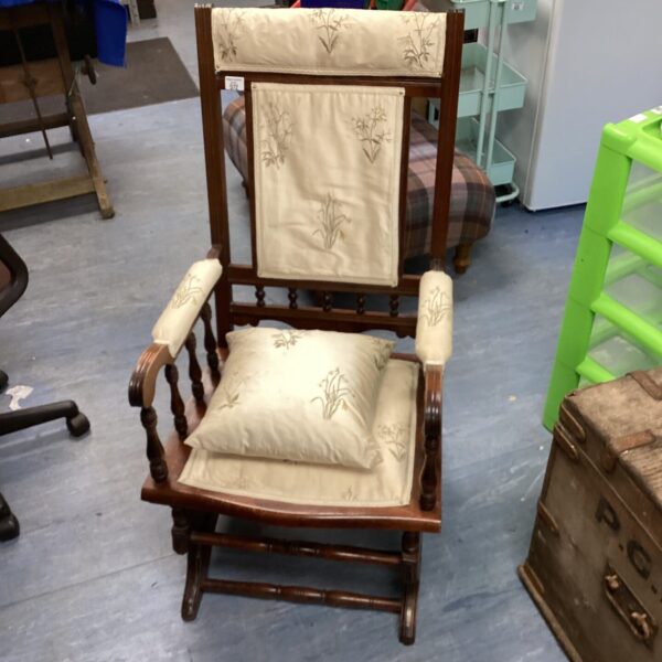 Antique rocking chair with a patterned cushion for comfortable seating.