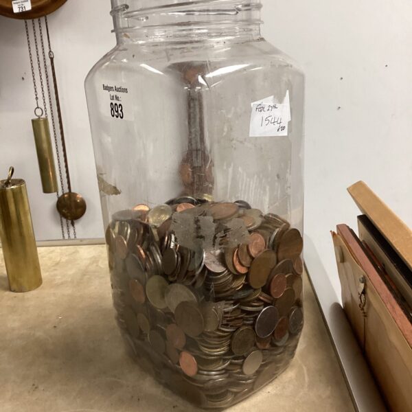 Glass jar filled with a diverse assortment of mixed coins.