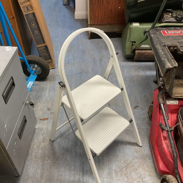 White metal kitchen step ladder in a garage setting.