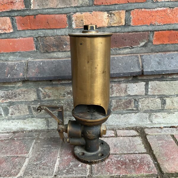 Vintage brass Crosby steam whistle against brick wall.