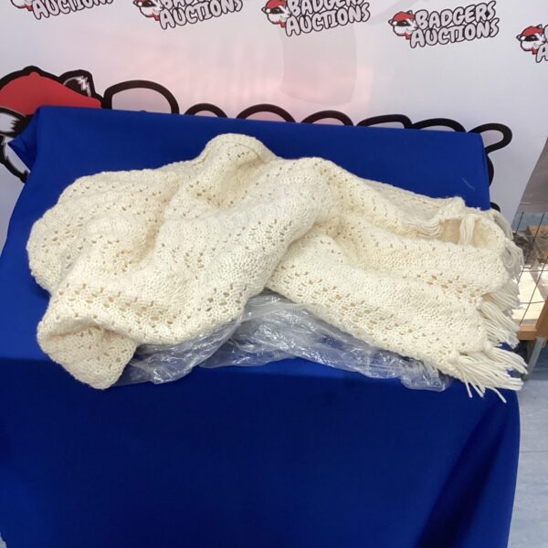 Close-up of a handmade crocheted wool blanket with textured stitching.