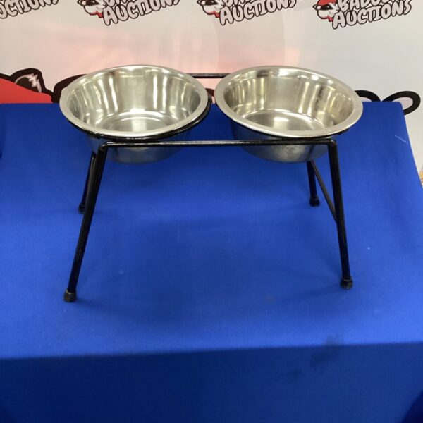 Stainless steel dog bowls on black frame for pet feeding.