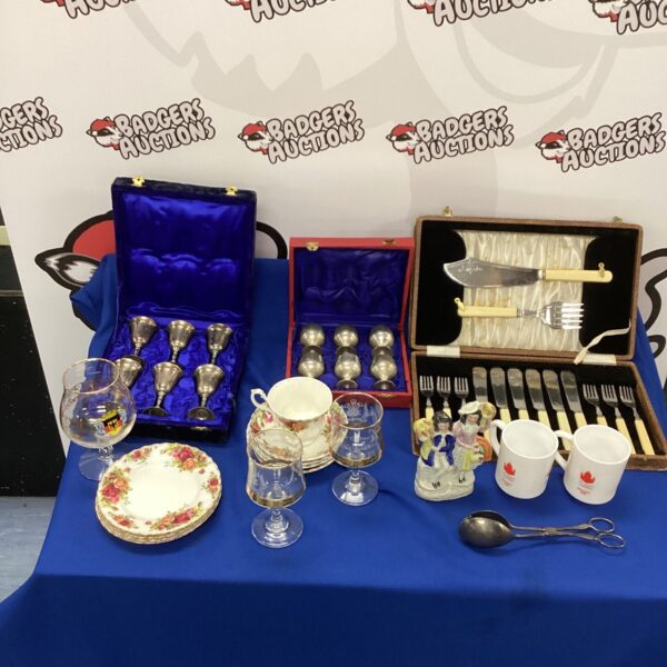 Mixed lot of silverplate goblets and vintage glassware on display.