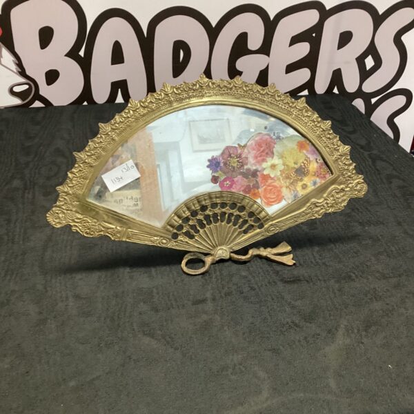 Ornate vintage brass fan shaped mirror for wall display.