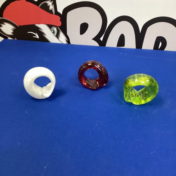Set of colourful Murano glass napkin rings on a dark surface.