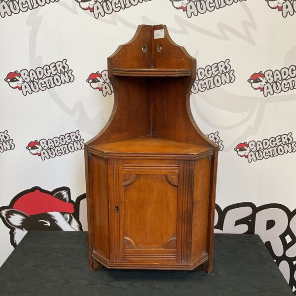 Antique corner shelf unit with a single door, vintage wooden display.
