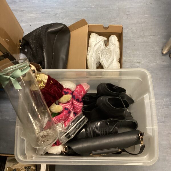 Mixed household lot with trainers and clothing inside a plastic box.