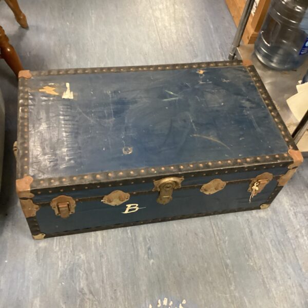 Front view of a vintage travel trunk with metal corner protectors.