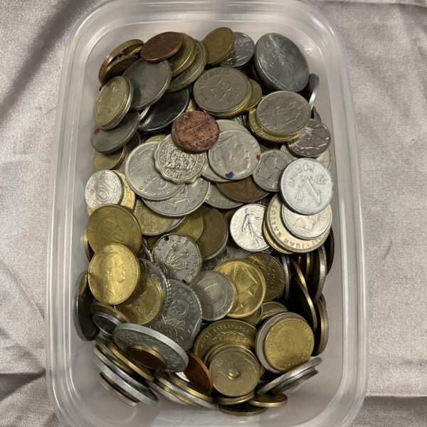Mixed coin lot in a clear tub, diverse world currencies.