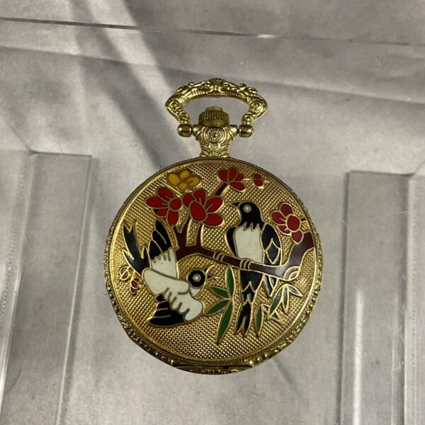 Vintage enamel pocket watch with floral and bird design.