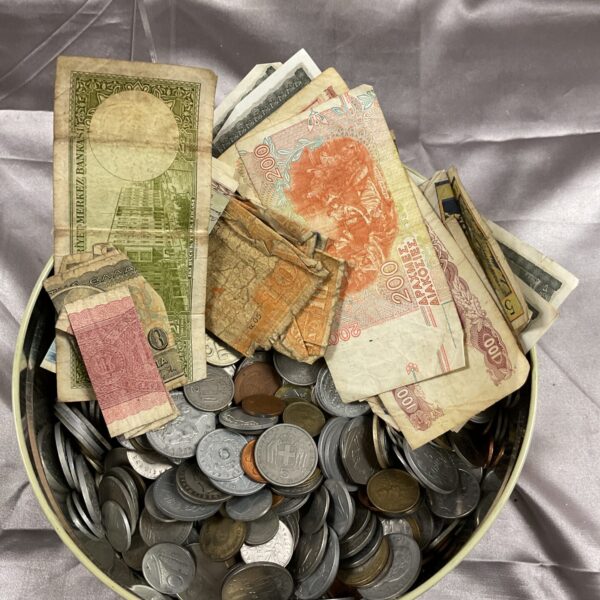 Tin filled with assorted coins and banknotes from around the world.