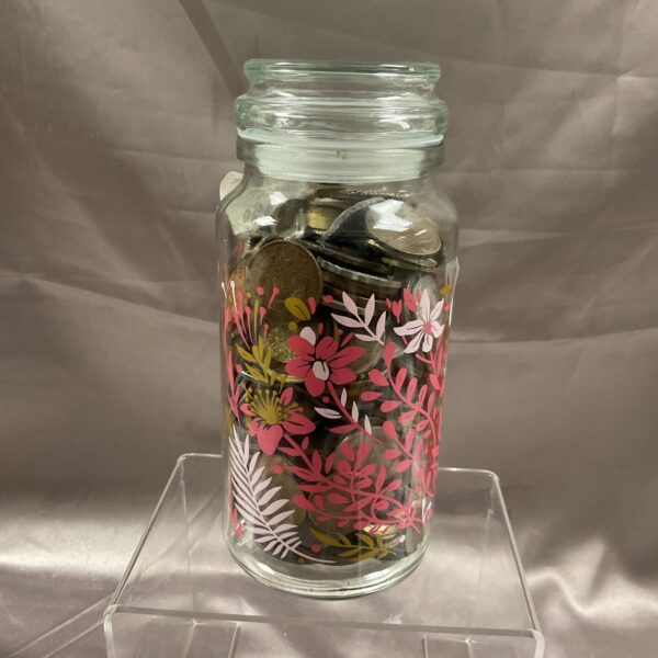 Vintage glass jar filled with assorted coins for collectors.