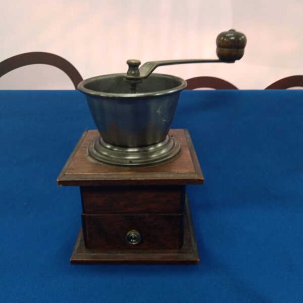 Front view of a vintage coffee mill with hand crank.
