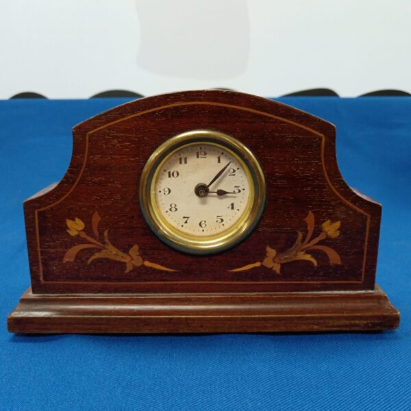 Antique mantle clock with inlaid wooden case and Roman numeral dial.