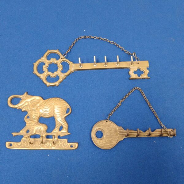 Vintage brass key hooks with elephant designs for wall mounting.