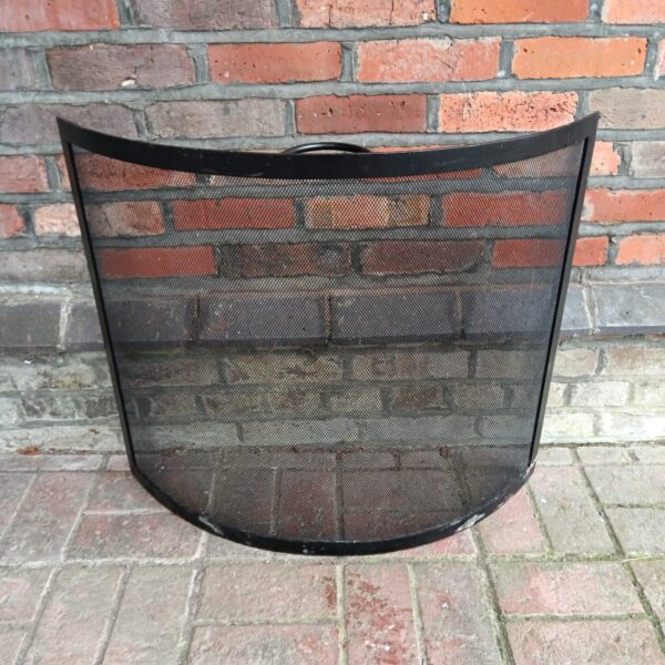Vintage iron firescreen with mesh panel for fireplace safety.