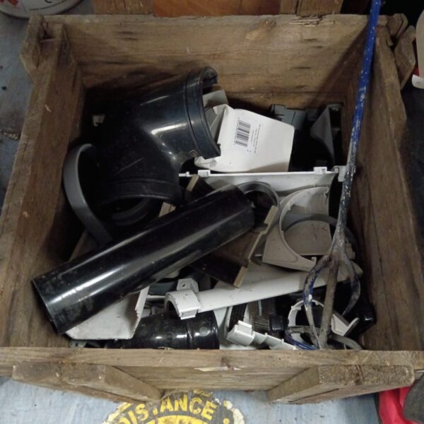 Assorted plumbing pipes and fittings in a wooden box.