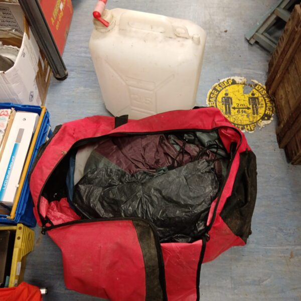 Camping tent in storage bag with a large water bottle.