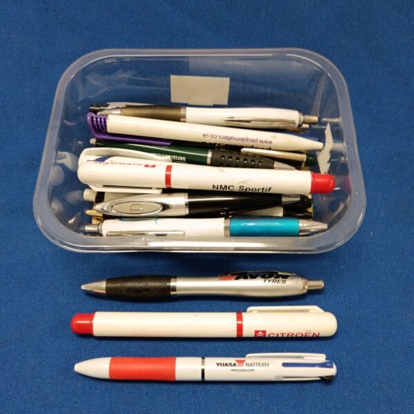 Mixed lot of assorted ballpoint pens in a clear tray.