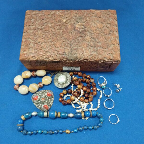 Vintage jewellery box filled with beaded necklaces and silver rings.
