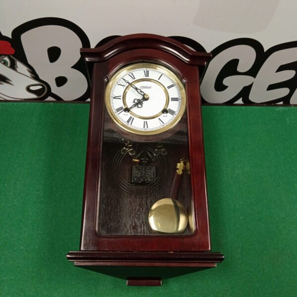 Front view of a vintage Highlands chiming wall clock with pendulum.