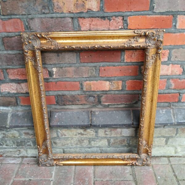 Ornate gilt picture frame with intricate carvings and gold finish.