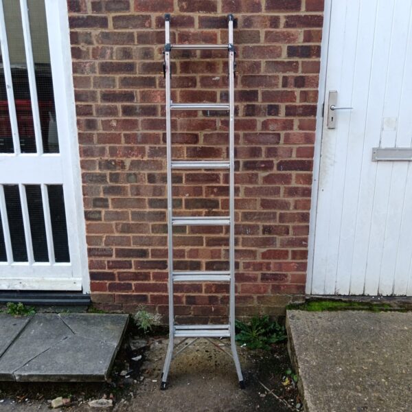 Silver combination aluminium ladder leaning against a brick wall.